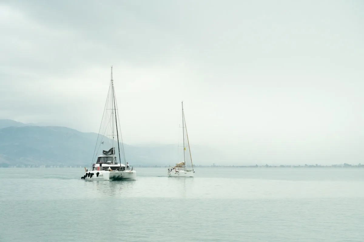 Sailboats on calm misty waters at dawn